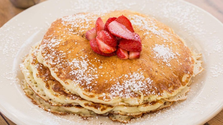 Stack of pancakes with powdered sugar and strawberries