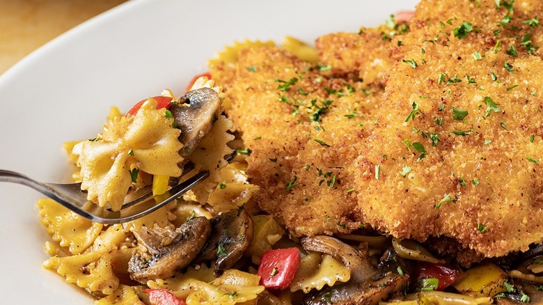 Fried chicken cutlet on bowtie pasta with mushrooms and peppers