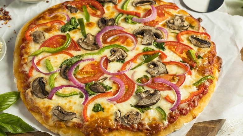 Pizza topped with vegetables on light background