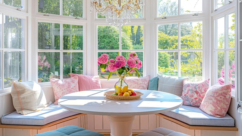 Bright breakfast nook with centerpiece on table and large windows in background