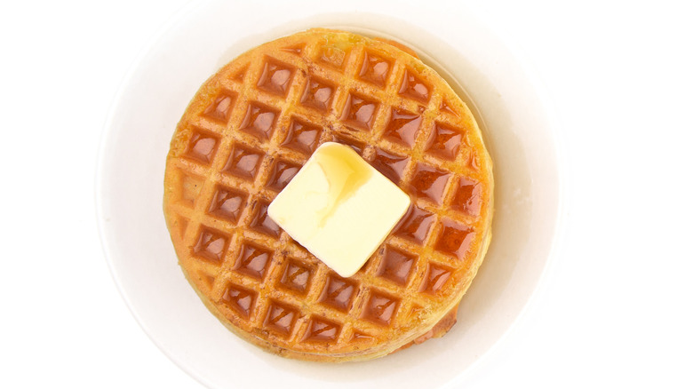 Round waffle with pat of butter on white plate