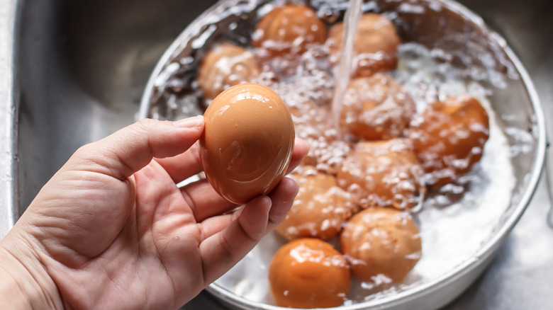 holding egg in front of bowl of eggs being filled with water