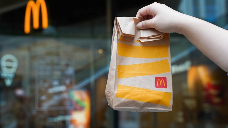 hand holds a mcdonald's bag
