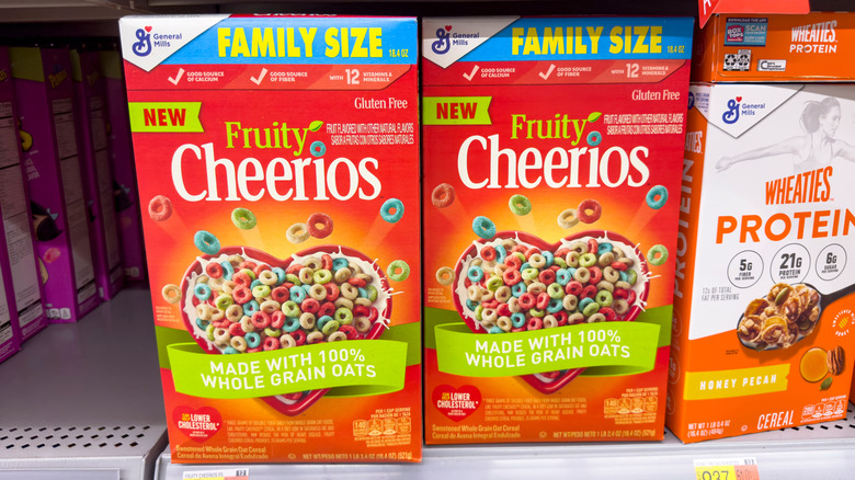 two boxes of fruity cheerios on a store shelf next to a box of wheaties honey peach