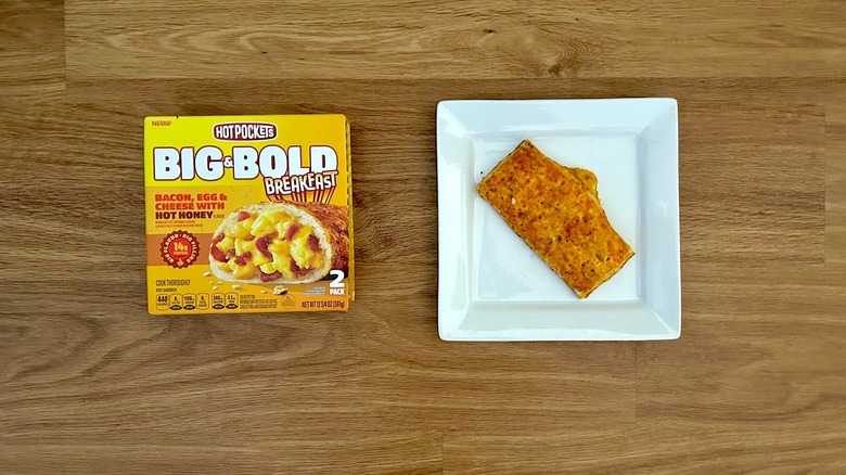 Hot Pockets Big & Bold Breakfast Bacon, Egg, & Cheese with Hot Honey package on wood counter and hot pocket on white plate.