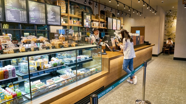 a woman orders starbucks with the pastry case on display