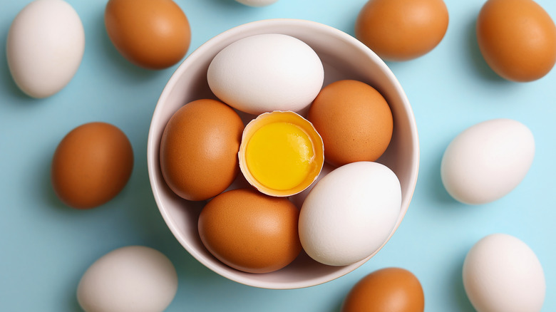 A bowl of white and brown eggs on a blue background