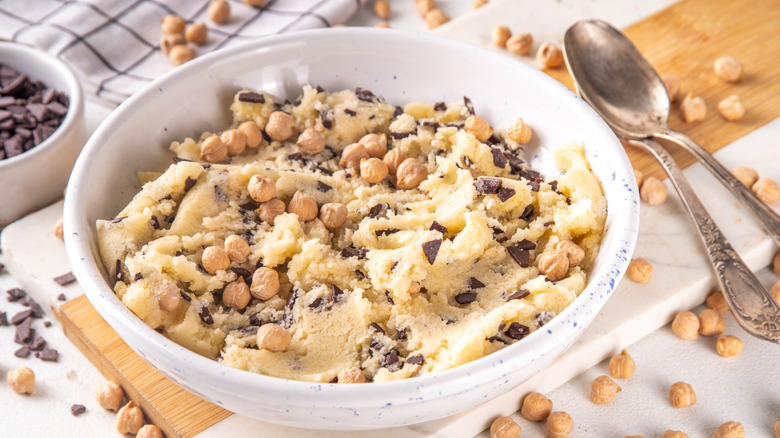 A bowl of raw chickpea cookie dough on a wood and marble cutting board