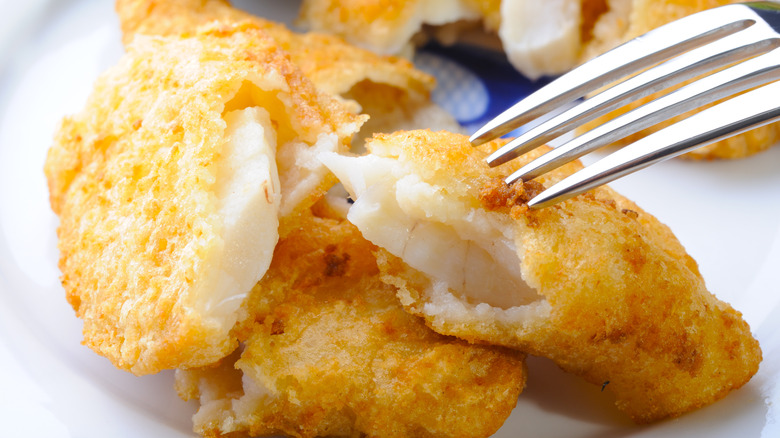 A close up of a fork and baked cod