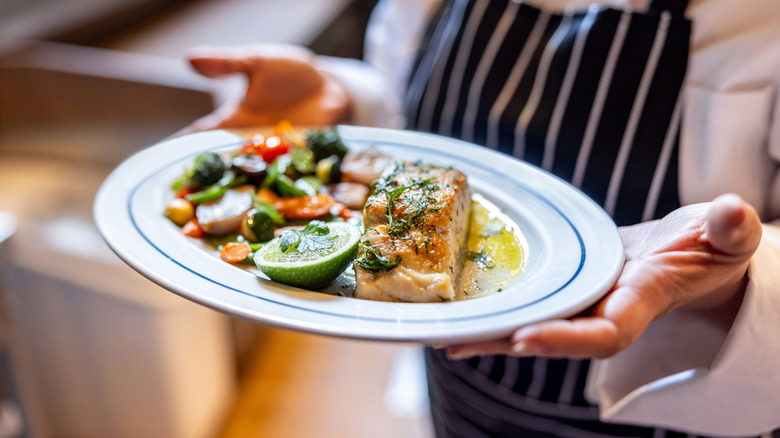 Close-up of a waiter holding a plate of food