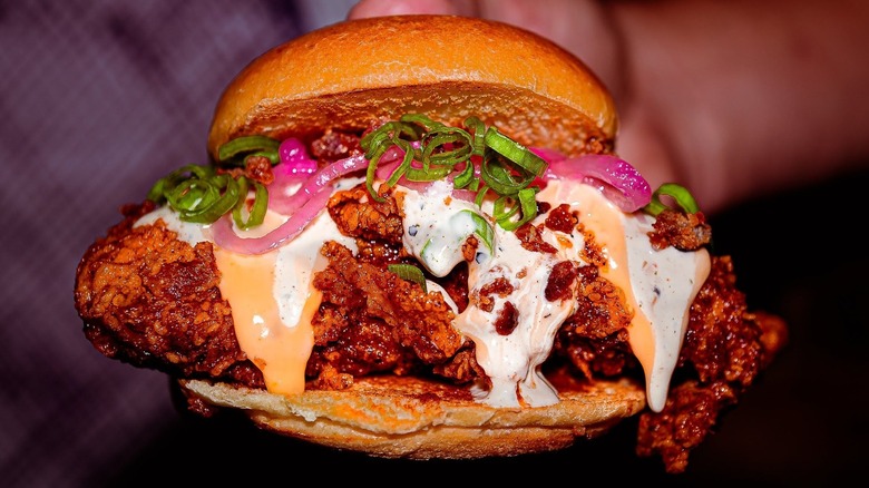 Someone holding a fried chicken sandwich from Royals Hot Chicken