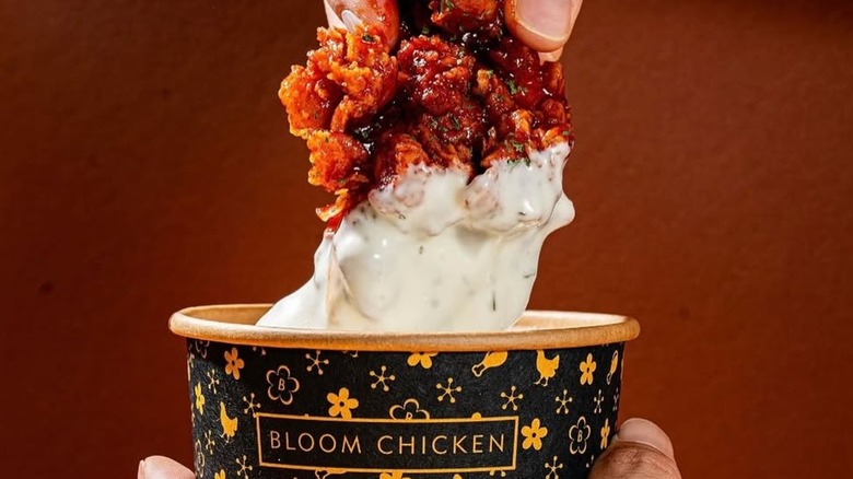 A Bloom Chicken fried chicken tender being dipped into sauce