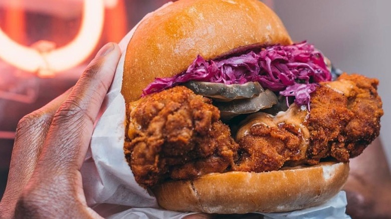 Someone holding up a fried chicken sandwich from Pretty Bird