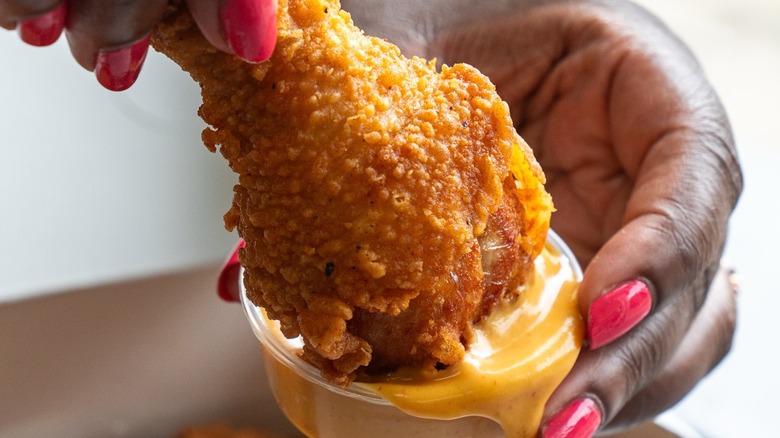 Dipping a fried chicken tender from Southern Style Chicken & Waffle