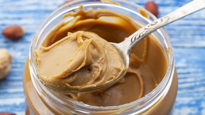A spoonful of peanut butter over an open jar