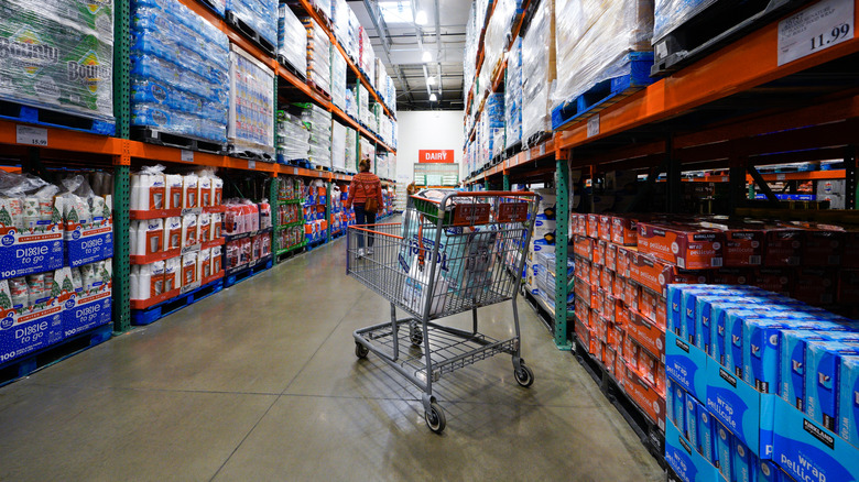 Costco shopping cart in aisle with pallets of products