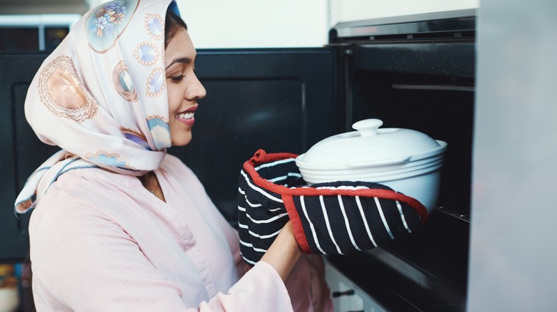 woman takes casserole pan from oven