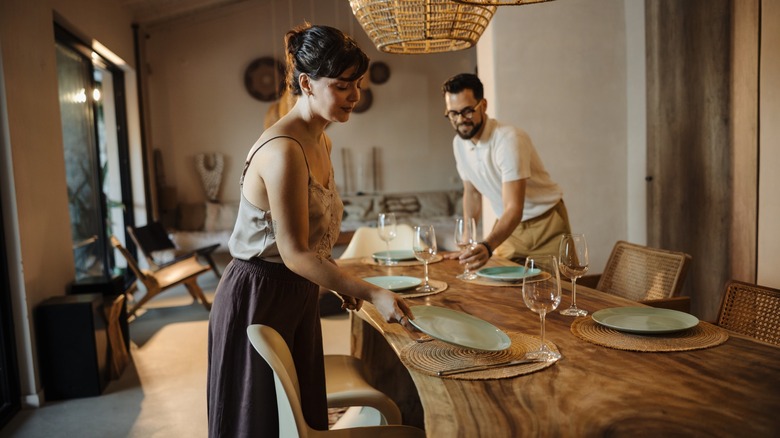 couple sets the table for dinner