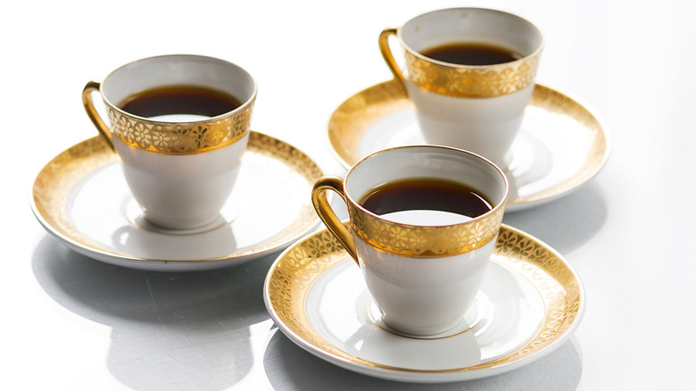 Closeup of three Limoges cups and saucers with gold detailing.
