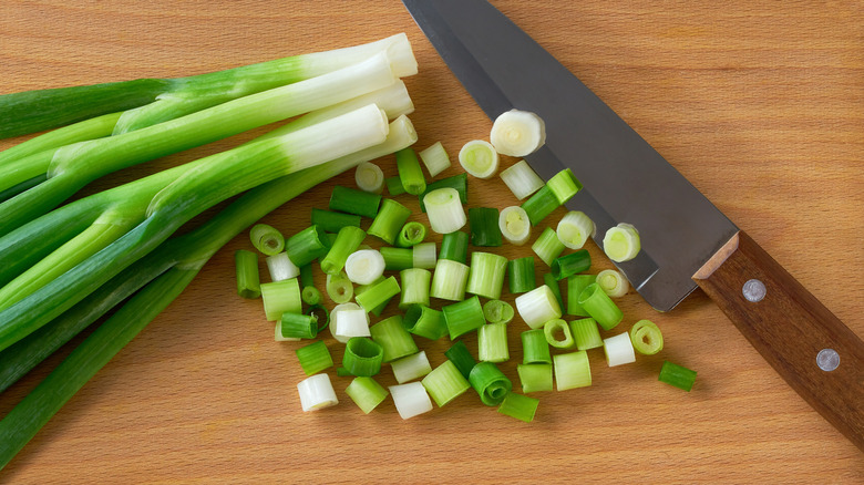 Chopped scallions on a wooden cutting board.