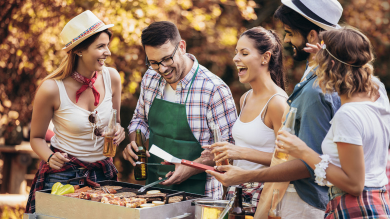 friends laughing gather around the grill for fun cookout