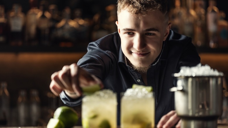 a bartender accents a caipirinha with a twist of lime