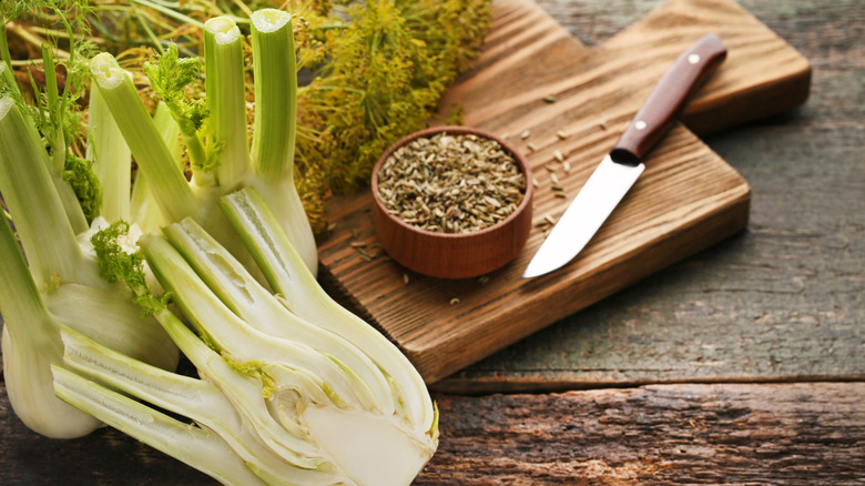 Fennel bulbs with fronds next to a bowl of fennel seeds