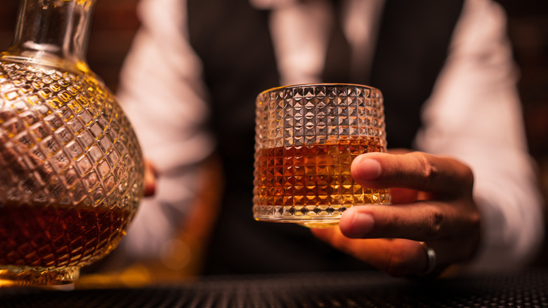 Bartender holding glass of whiskey, closeup