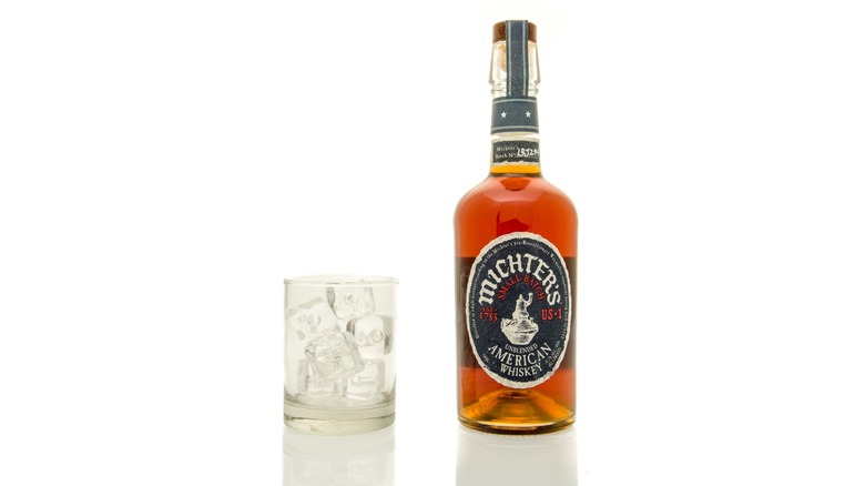 bottle of sealed michter's american whiskey with ice cubes in glass