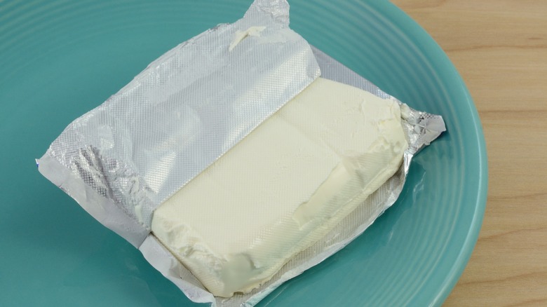 unwrapped block of cream cheese on blue plate