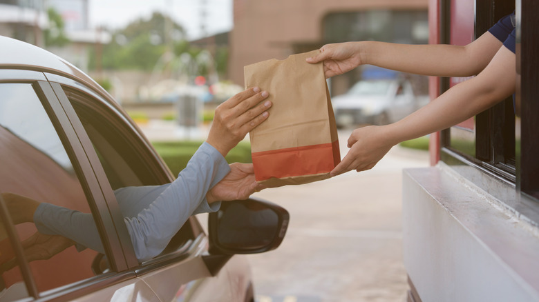 Customer picks up bag at fast food drive-thru