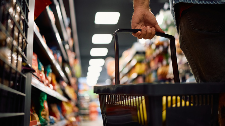 Closeup of person holding shopping basket, bananas inside