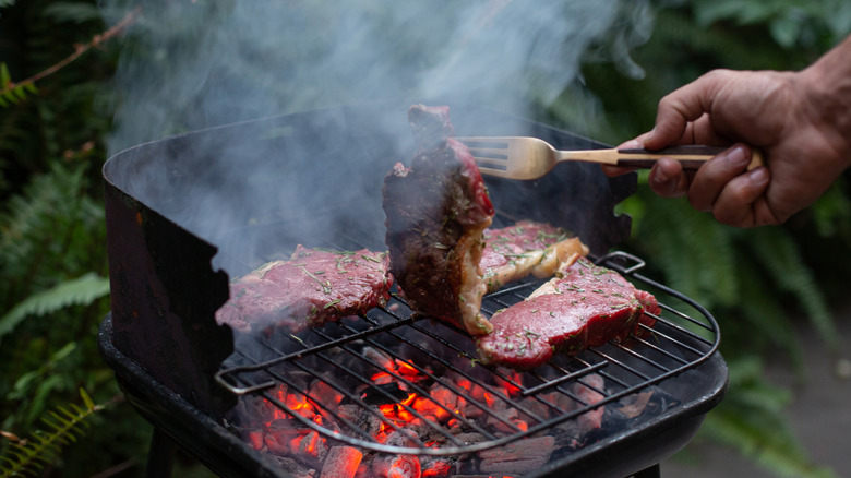 A close-up of a charcoal grill with meat on top