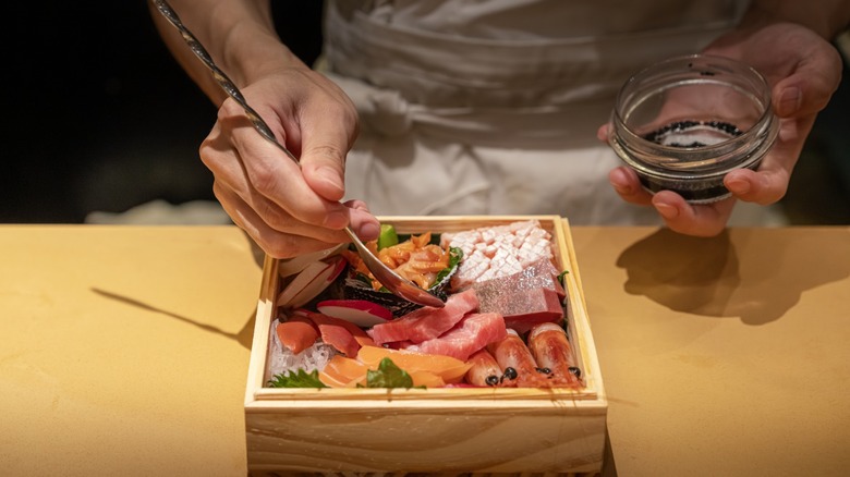 sushi in a box with spoon and sauce