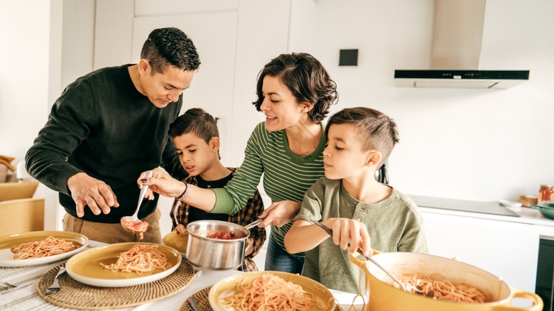 family serves pasta onto plates