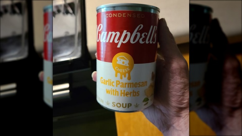 a hand holds a can of campbell's garlic parm cheese soup