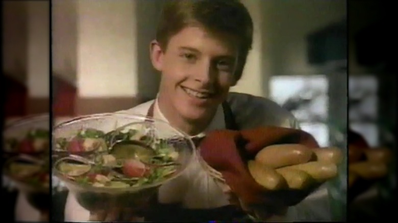 smiling olive garden server displays breadsticks and salad