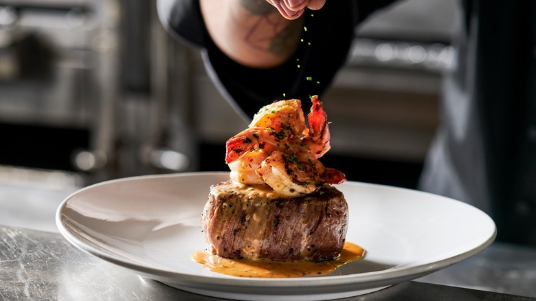 seasoning a surf and turf dish on plate