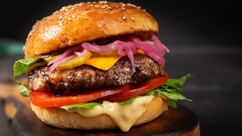 close up of juicy burger with pickled onions