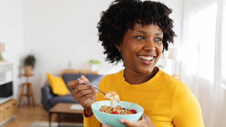 A smiling young woman eating cereal