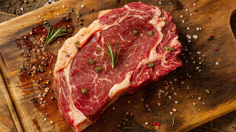 Raw ribeye on a wooden block