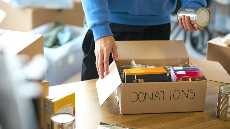Someone packing a box of food bank donations.