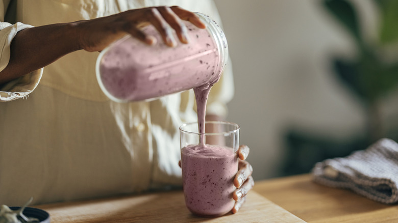 Someone pouring a smoothie from a blender into a glass