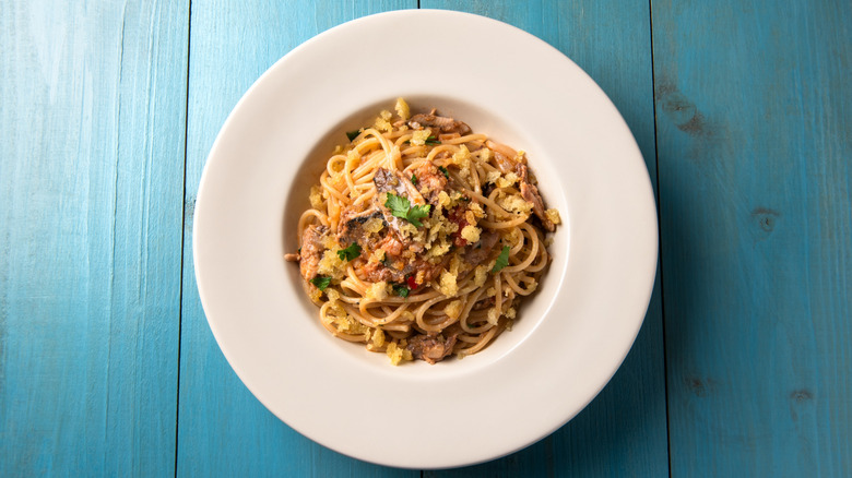 Top-down view of a bowl of pasta con le sarde on a blue wooden background