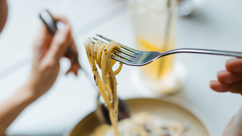 Someone eating a forkful of pasta