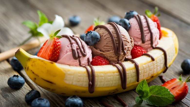 A banana split with strawberry and chocolate ice cream, chocolate sauce, and fresh berries
