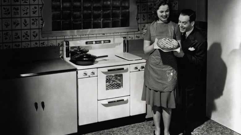 b&w photo of woman and man in kitchen with pie