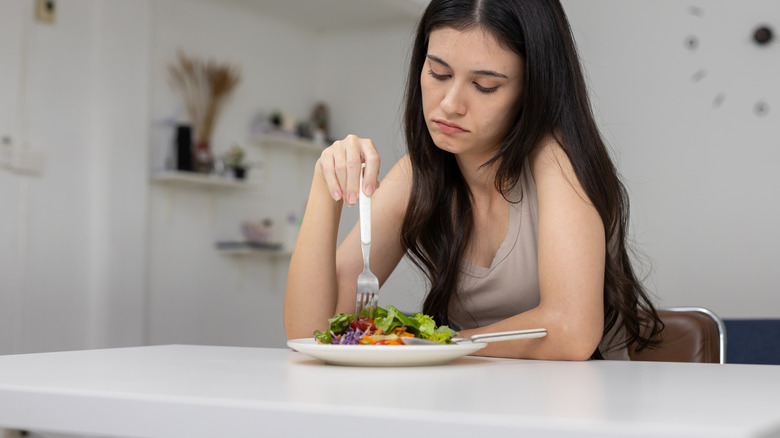Women looking bored eating salad.