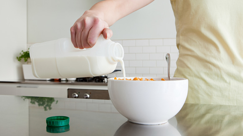 Someone pouring milk into a bowl of cereal