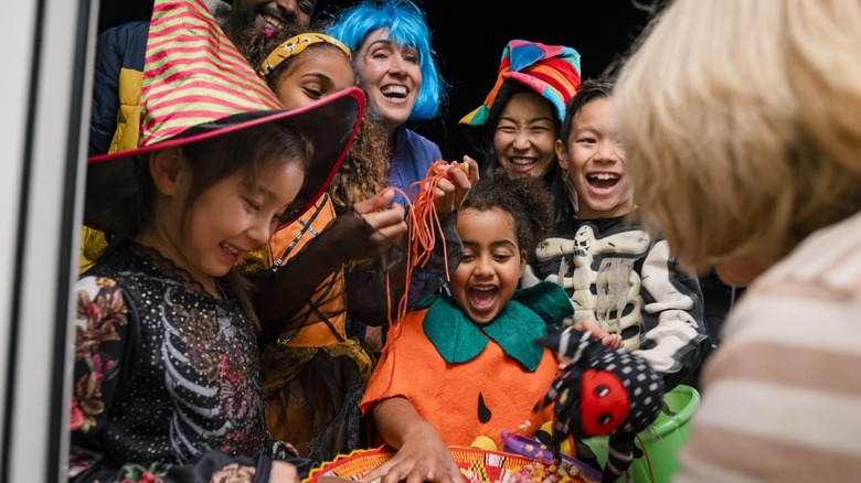 kids in halloween costumes grab at a candy bowl